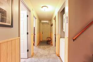 A hallway with a carpeted floor, wooden walls, and a door at the end. - Miracle Mountain Cabin Secluded Mountain Getaway (Bryson City)