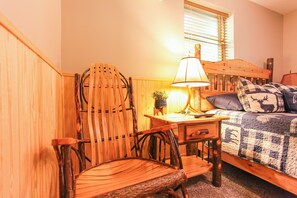 Un dormitorio acogedor con una cama de madera, un escritorio con lámpara y una silla.