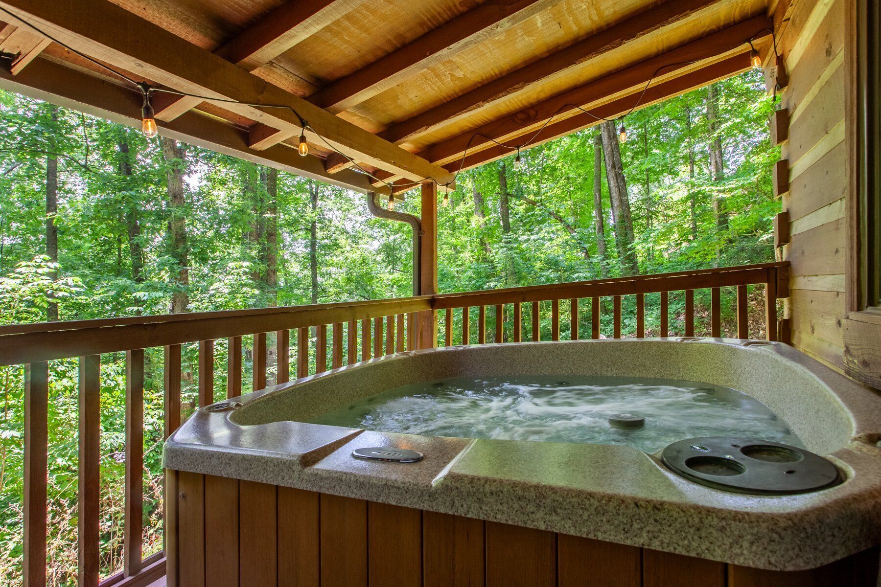 Ein Whirlpool mit einer Holzterrasse und Blick auf einen Wald.