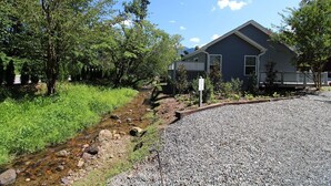 A house with a gravel driveway and a small stream running alongside.