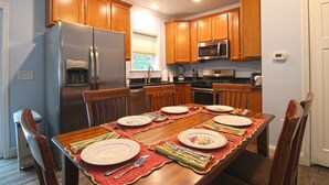 A modern kitchen with wooden cabinets, stainless steel appliances, and a dining table set for four.