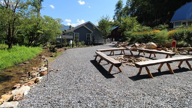 A gravel area with picnic tables and a stream.