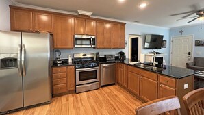 Una cocina moderna con armarios de madera, electrodomésticos de acero inoxidable y encimera negra.