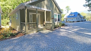 A small, single-story house with a porch and a gravel driveway. - Cuddle Cove Modern, Creekside Home right by the Heart of Bryson City (Bryson City)