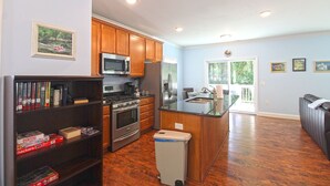 A modern kitchen with wooden cabinets, stainless steel appliances, and a built-in island with a sink. - Cuddle Cove Modern, Creekside Home right by the Heart of Bryson City (Bryson City)