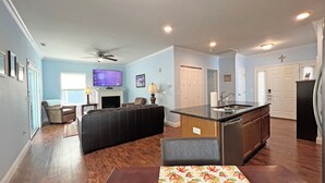 A spacious living area with a fireplace, a television, and a kitchen island. - Cuddle Cove Modern, Creekside Home right by the Heart of Bryson City (Bryson City)