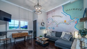 A modern living room with a large wall map, a wooden coffee table, a sofa, and a TV mounted on the wall.