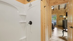A wooden interior with a white door, a ceiling fan, and a bench.