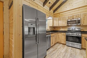 A modern kitchen with stainless steel appliances, wooden cabinets, and a built-in oven. - Magical Memories Brand New Veranda Level Cabin Overlooking Pond in Heart of Bryson City (Bryson City)