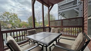 Überdachte Terrasse mit Tisch und Stühlen, mit Blick auf ein Gewässer und eine Wohngegend.