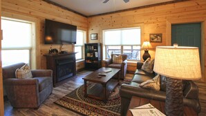 Ein gemütliches Wohnzimmer mit Kamin, Fernseher, Bücherregal und einer bequemen Sitzecke.