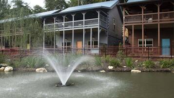 A building with a water fountain in front, wooden structures, and a natural setting.