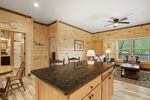 A wooden interior with a kitchen island, dining area, and seating space. - Huggie Bear Located in Bryson Village in Town. Pet Friendly! (Bryson City)