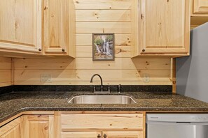 A kitchen with wooden cabinets, a granite countertop, a stainless steel sink, and a dishwasher.