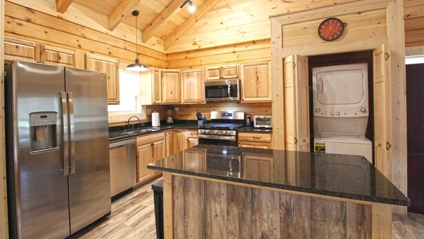 A modern kitchen with wooden cabinets, stainless steel appliances, and a granite countertop. - Moose Tracks Downtown Veranda Level Cabin with Hot Tub (Bryson City)