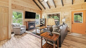 Un intérieur de chalet chaleureux avec une cheminée, un coin salon et un téléviseur.
