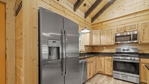 Una cocina moderna con electrodomésticos de acero inoxidable, armarios de madera y una lámpara colgante.