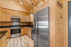 Une cuisine avec des meubles en bois, des appareils électroménagers en acier inoxydable et un plancher en bois.