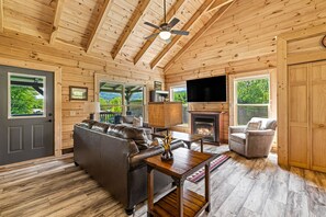 Un intérieur en bois avec une cheminée, un canapé en cuir et un téléviseur.