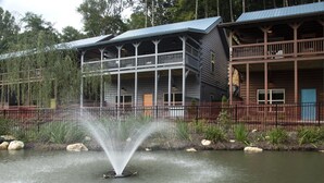 A rustic lodge with a large porch and a fountain in front.