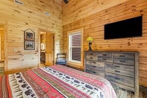 Une chambre dans une cabane en bois, avec un lit, une commode et un téléviseur.