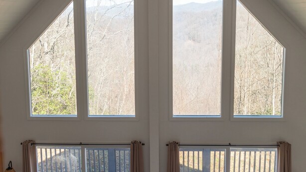 A room with large windows, a wooden deck, and a view of trees and mountains. - Hidden Mountain Retreat Absolute Seclusion near Cherokee (Whittier)