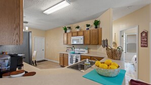 A kitchen with wooden cabinets, a microwave, a sink, and a bowl of lemons on the counter. - Pet friendly Pool Home with King suite 10 minutes to Disney World (Davenport)