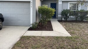 A residential house with a garage, a front door, and a small garden area. - Pet friendly Pool Home with King suite 10 minutes to Disney World (Davenport)