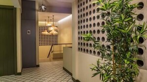 Käytävän lattia on kuvioitu, seinässä on pyöreitä aukkoja ja siellä on myös ruukussa oleva kasvi.