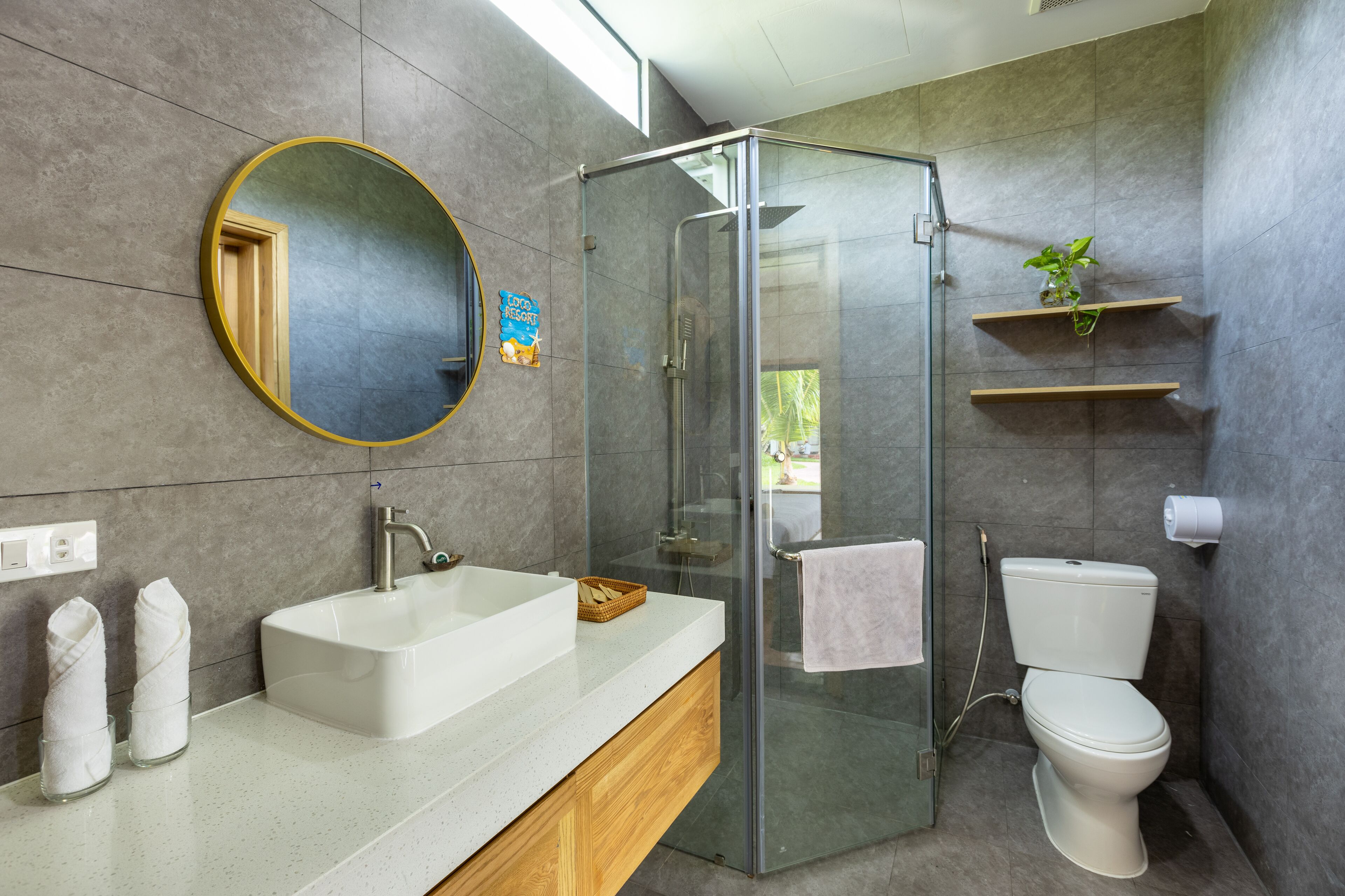 Ein modernes Badezimmer mit einer Duschkabine aus Glas, einem weißen Waschbecken und einer Toilette.