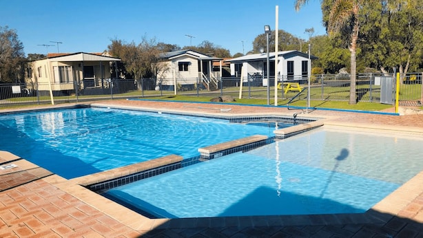 A rectangular swimming pool with a tiled edge, surrounded by a brick deck.