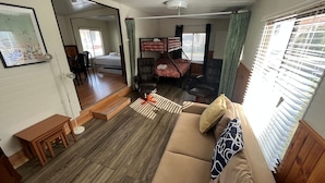 A compact living space with a sofa, a small table, a bunk bed, and a chair.