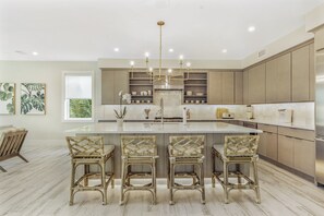 Una cocina moderna con una isla central, armarios empotrados y un refrigerador de acero inoxidable.