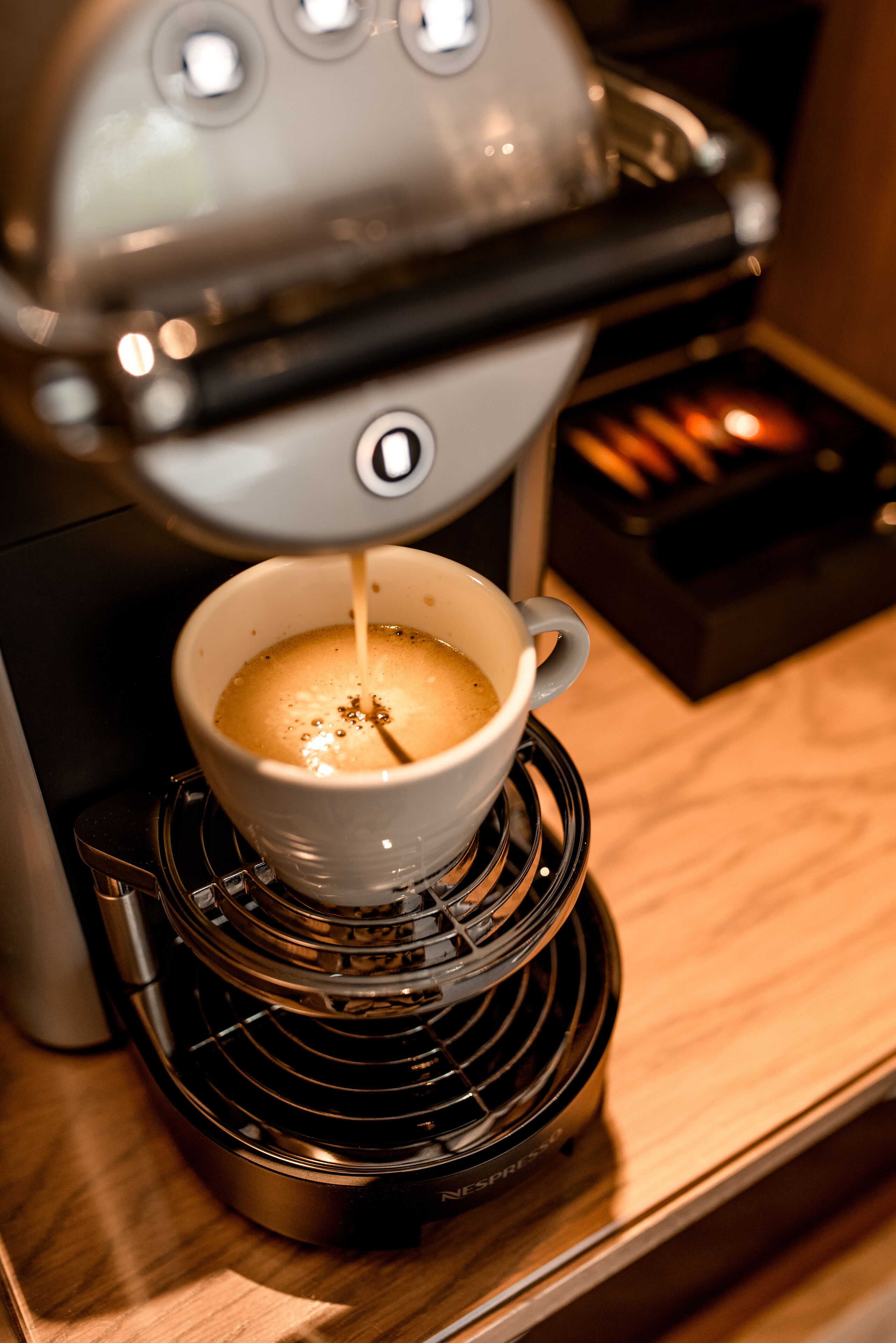 Una macchina per il caffè eroga caffè in una tazza su un vassoio riscaldato.