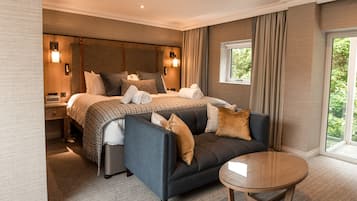 A hotel room with a large bed, a sofa, a small table, and a window with curtains.