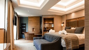 Ein modernes Hotelzimmer mit Sofa, Bett mit Kopfteil, kleinem Tisch und einer eingebauten Ablage.