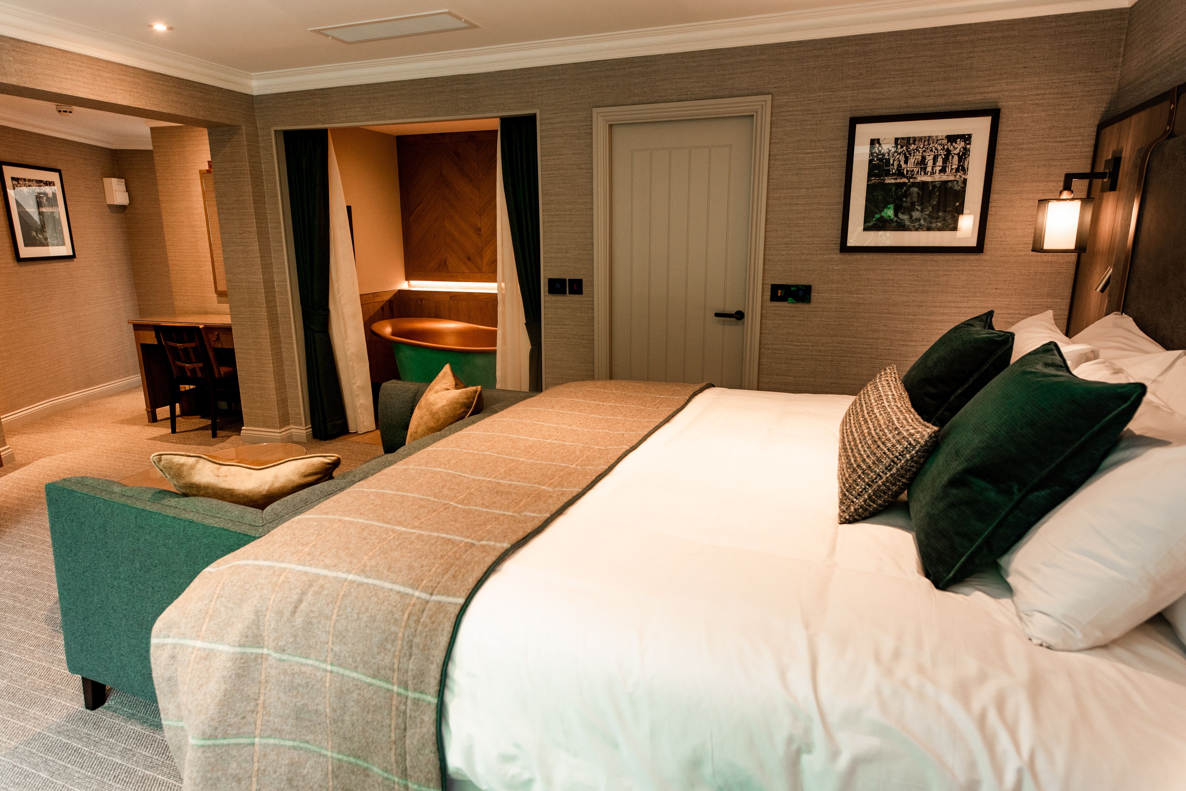 Une chambre d’hôtel avec un grand lit, un bureau avec une chaise, une petite salle de bain et une porte donnant sur une autre chambre.