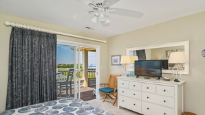 Ein Schlafzimmer mit einem Bett, einem Schminktisch, einem Fernseher und Blick ins Freie.