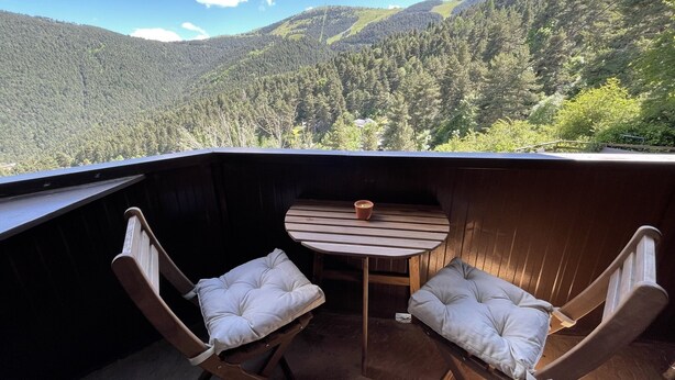A wooden deck with two cushioned chairs and a small table, overlooking a forested mountain landscape. - Apartamento en La Molina, Grandes Vistas, Chimenea (La Molina, Alp)