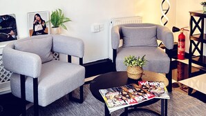 Ein modernes Wohnzimmer mit zwei grauen Sesseln, einem runden Spiegel und einem Couchtisch mit einer Zeitschrift.