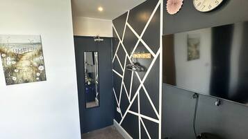 A modern bathroom with a geometric wall design, a mirror, a sink, and a vanity with a clock and decorative items.