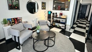 Ein Wohnzimmer mit Sofa, Sessel, Couchtisch und einer Kaffeemaschine.