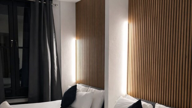 Ein Hotelzimmer mit zwei Betten, einer Wand aus Holzpaneelen und einem großen Fenster.