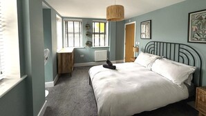 A bedroom with a bed, a desk, and a radiator. There are windows with shutters and a hanging light fixture. - Bernard Point (Southampton)