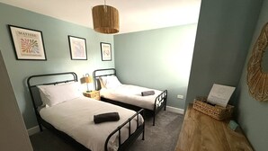 A bedroom with two beds, a hanging light fixture, and framed artwork on the wall. - Bernard Point (Southampton)