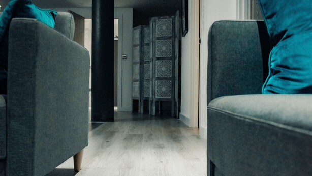 A modern living room with grey sofas and a wooden floor.