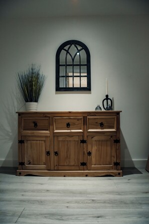 Ein Holzschrank mit Schubladen und einem Spiegel darüber, an einer Wand platziert.