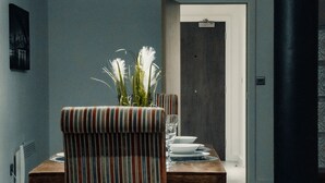 A dining area with a wooden table, striped upholstered chair, and a tufted grey sofa.