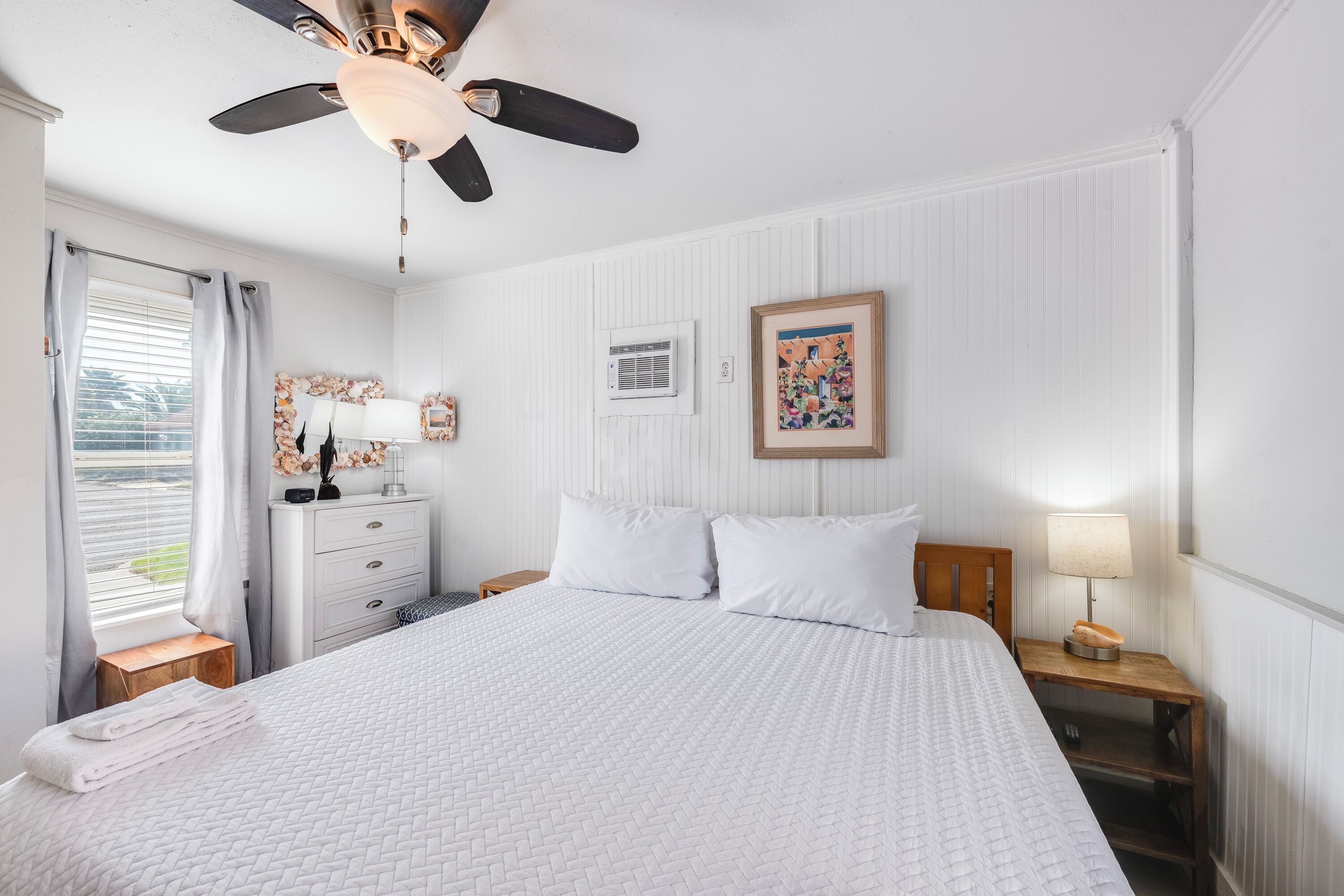 Drift off in your cozy bedroom with crisp white linens, coastal charm, and gentle ceiling fan keeping you comfortable all night.