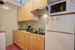 Une cuisine avec des meubles de rangement en bois, un four à micro-ondes, une cuisinière et un réfrigérateur.